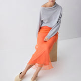 Woman wearing a gray sweater and orange skirt on a white background