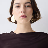 Woman wearing large earrings against a plain background