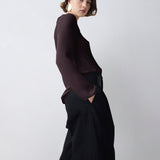 Person wearing a dark outfit against a plain background