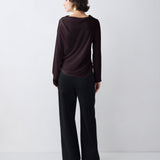 Woman wearing a dark brown long-sleeve top and black wide-leg pants on a white background