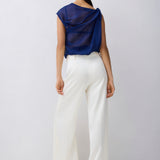 Person wearing a blue top and white pants on a plain background