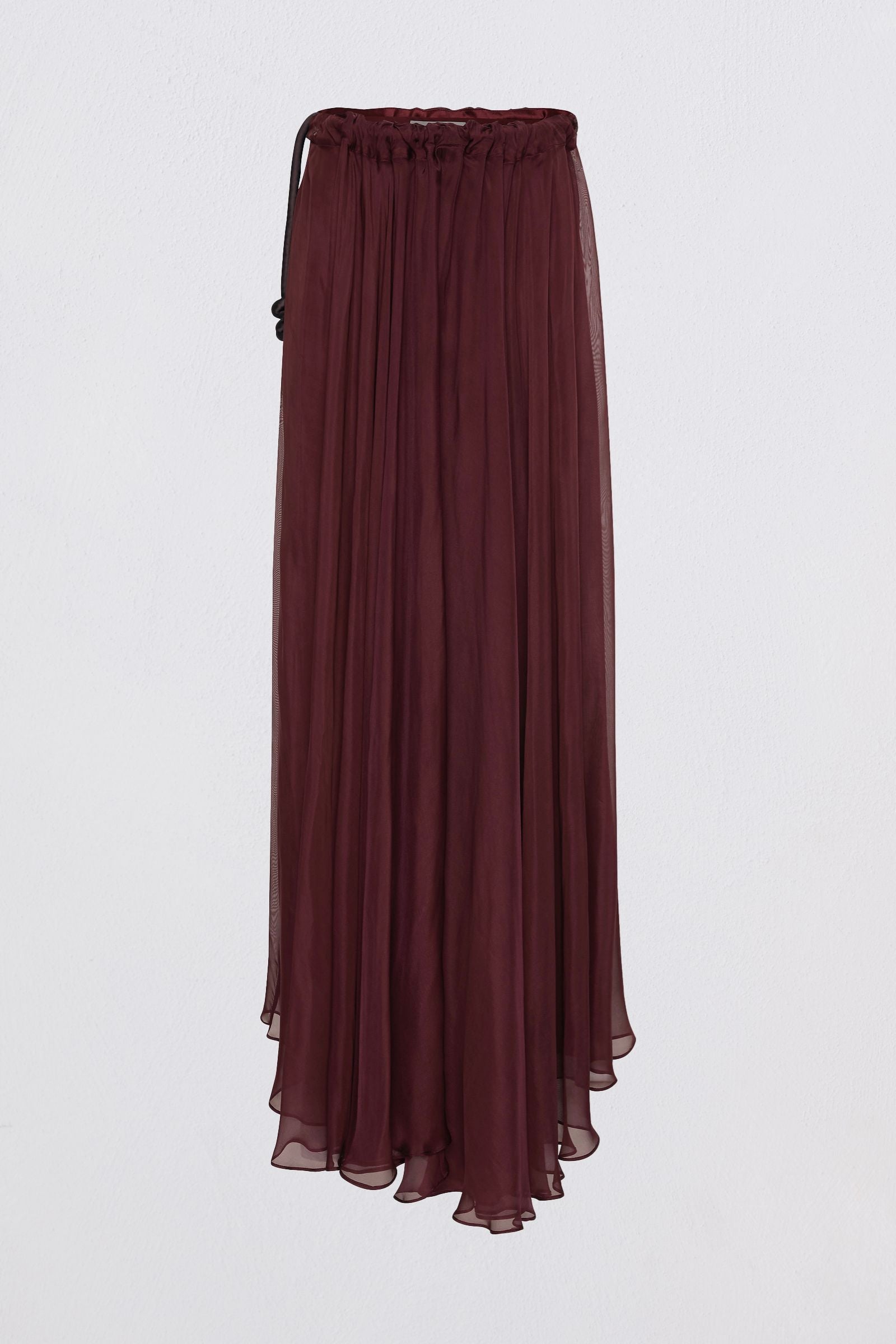 A woman wearing a deep burgundy off-the-shoulder maxi dress with a flowing skirt, shown from the back against a light gray studio background.