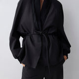 Person wearing a black outfit with a belt against a white background