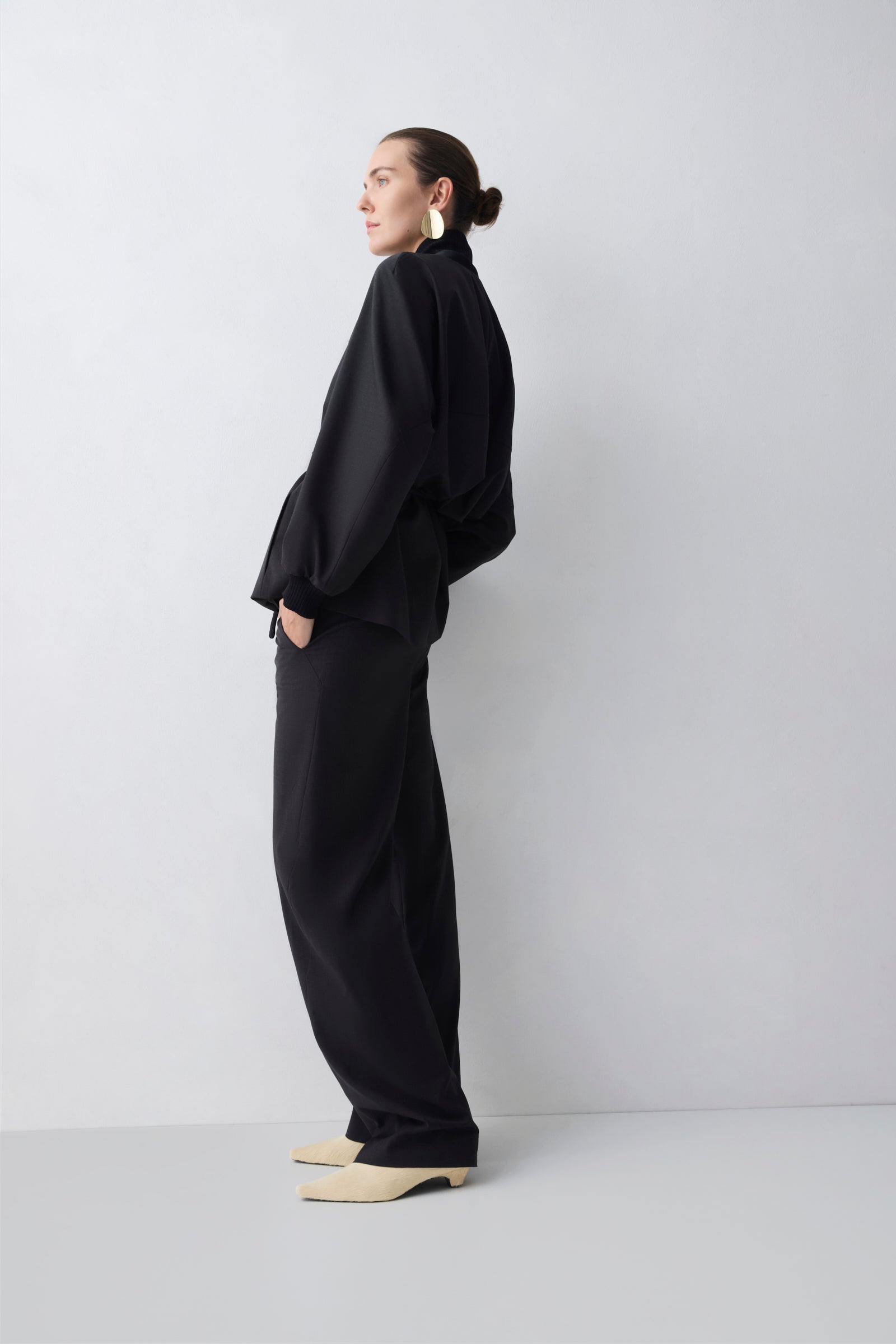 Person wearing a black outfit standing against a white background