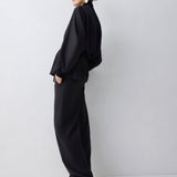 Person wearing a black outfit standing against a white background