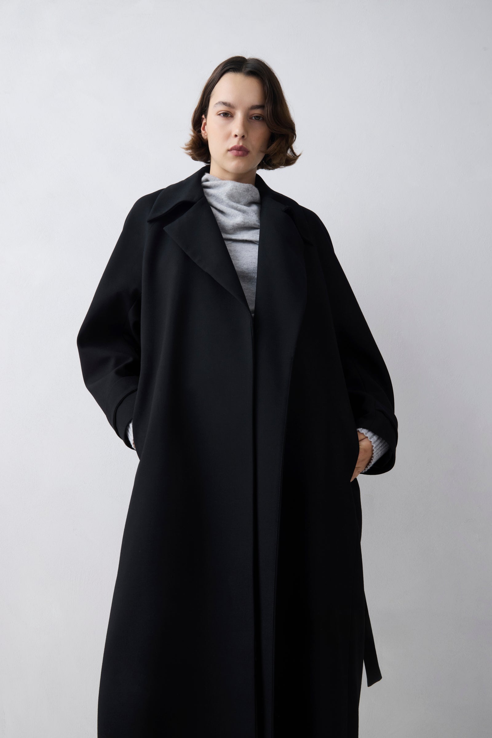 Person wearing a black coat on a white background