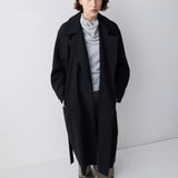 Person wearing a black coat and gray outfit on a white background