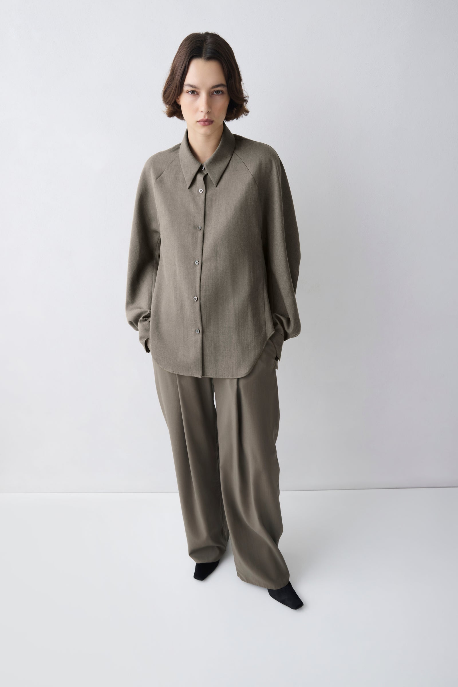 Person wearing a matching olive green shirt and pants set on a white background