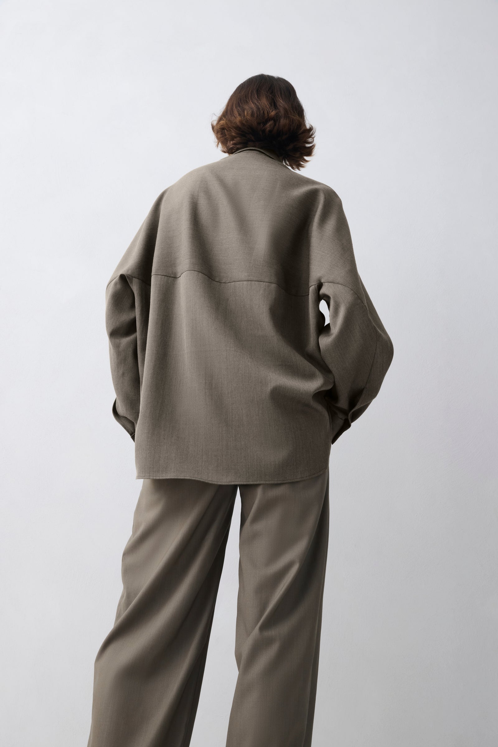 Person wearing a matching olive green jacket and pants on a white background