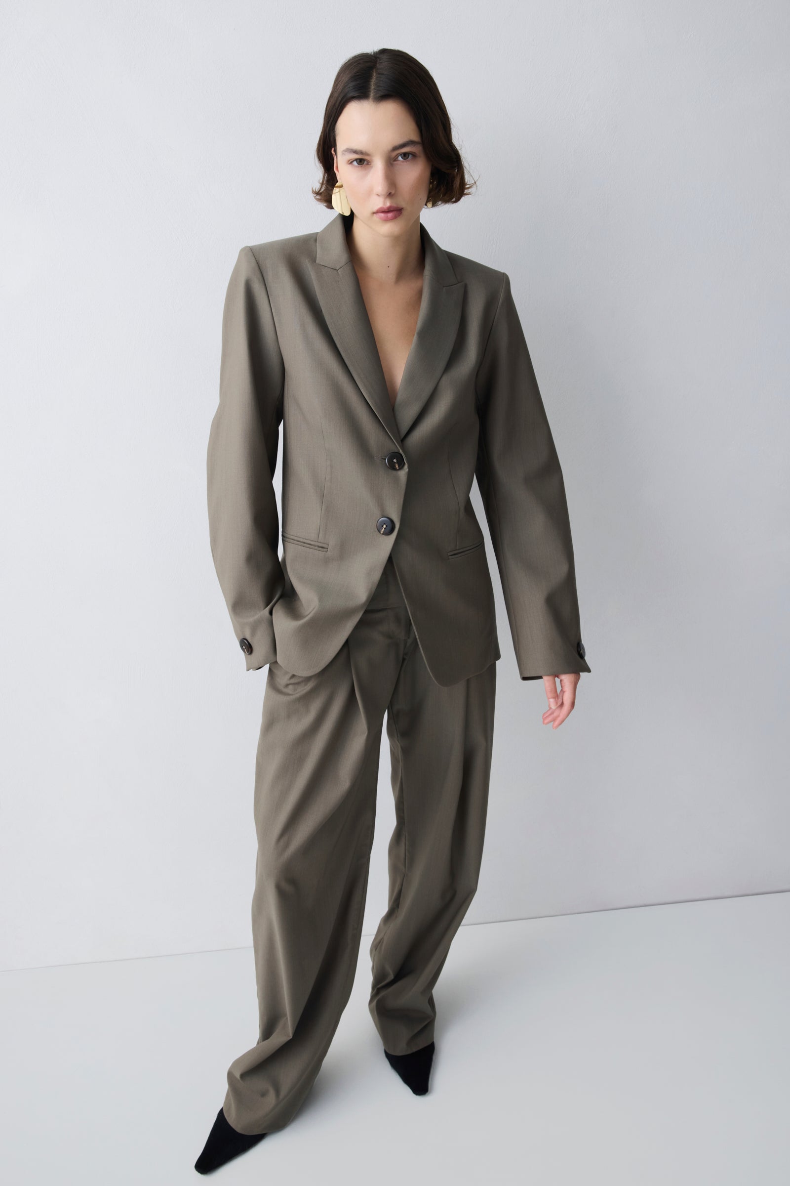 Person wearing a gray suit against a white background