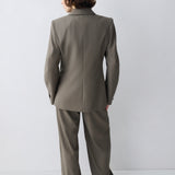 Person wearing a gray suit standing against a white background