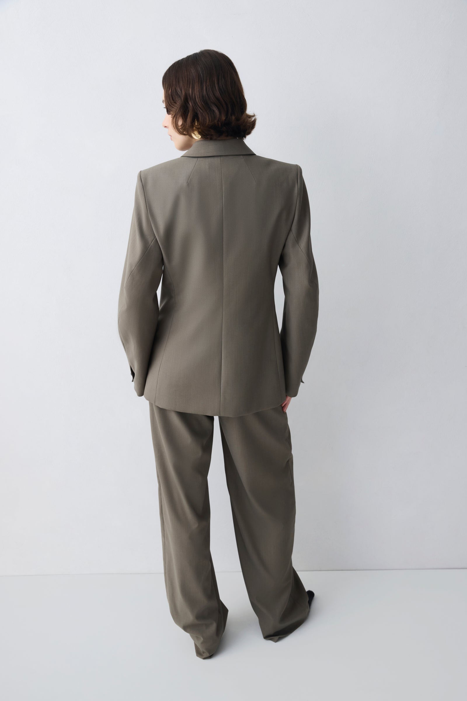 Person wearing a gray suit standing against a white background