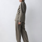 Woman wearing a green suit standing against a white background