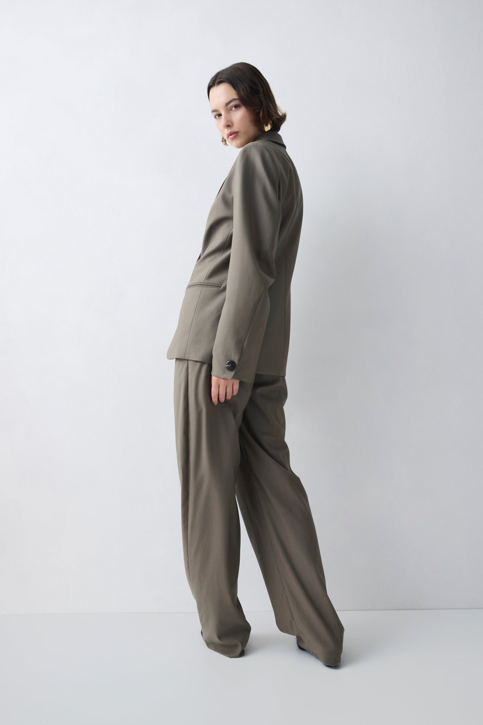 Woman wearing a green suit standing against a white background