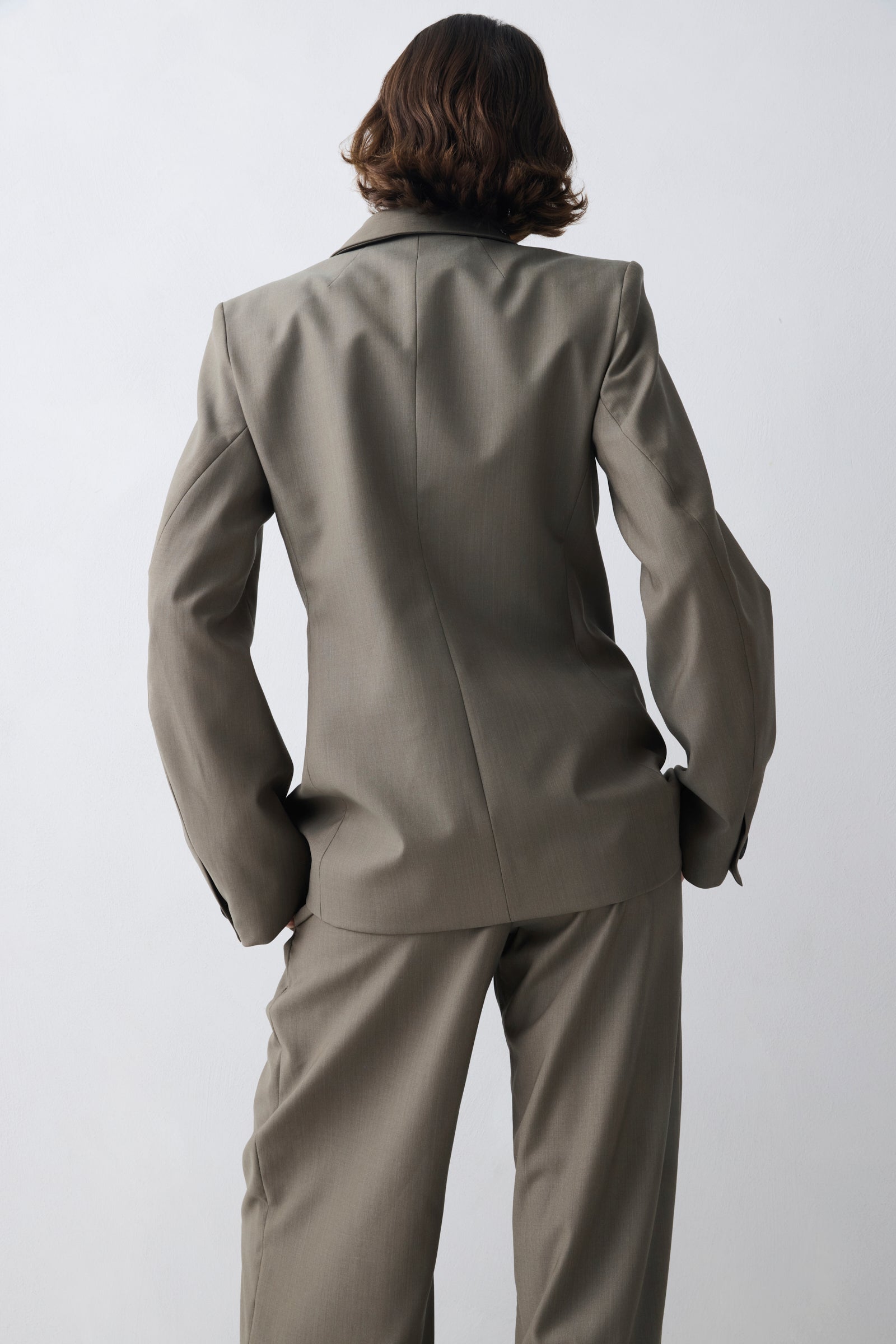 Person wearing a gray suit against a white background