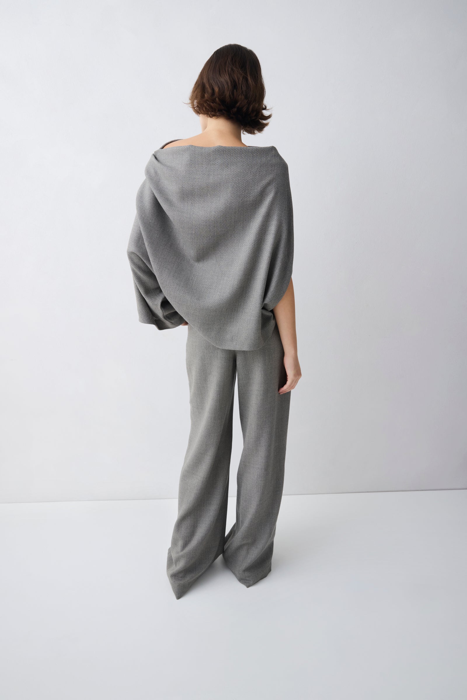 Person wearing a grey top and wide-leg pants on a white background