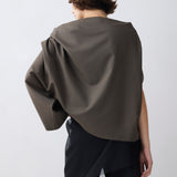 Person wearing a dark green cape over a plain background