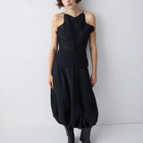 Woman wearing a black sleeveless top and skirt with black boots against a white background