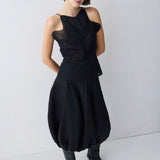 Woman wearing a black sleeveless top and black pants on a white background