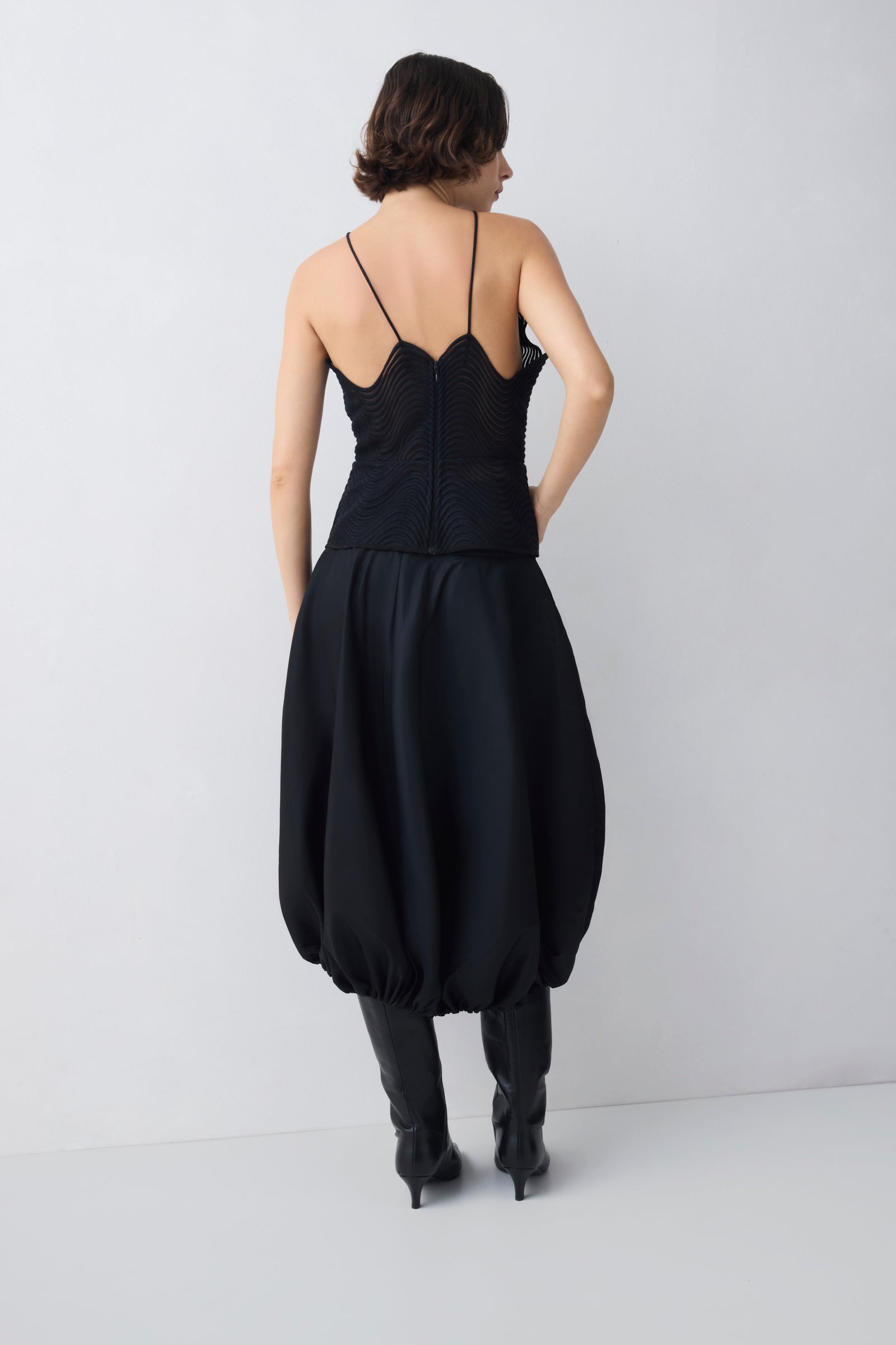 Person wearing a black dress with a plain background