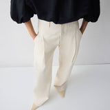 Person wearing a black top and white pants on a white background