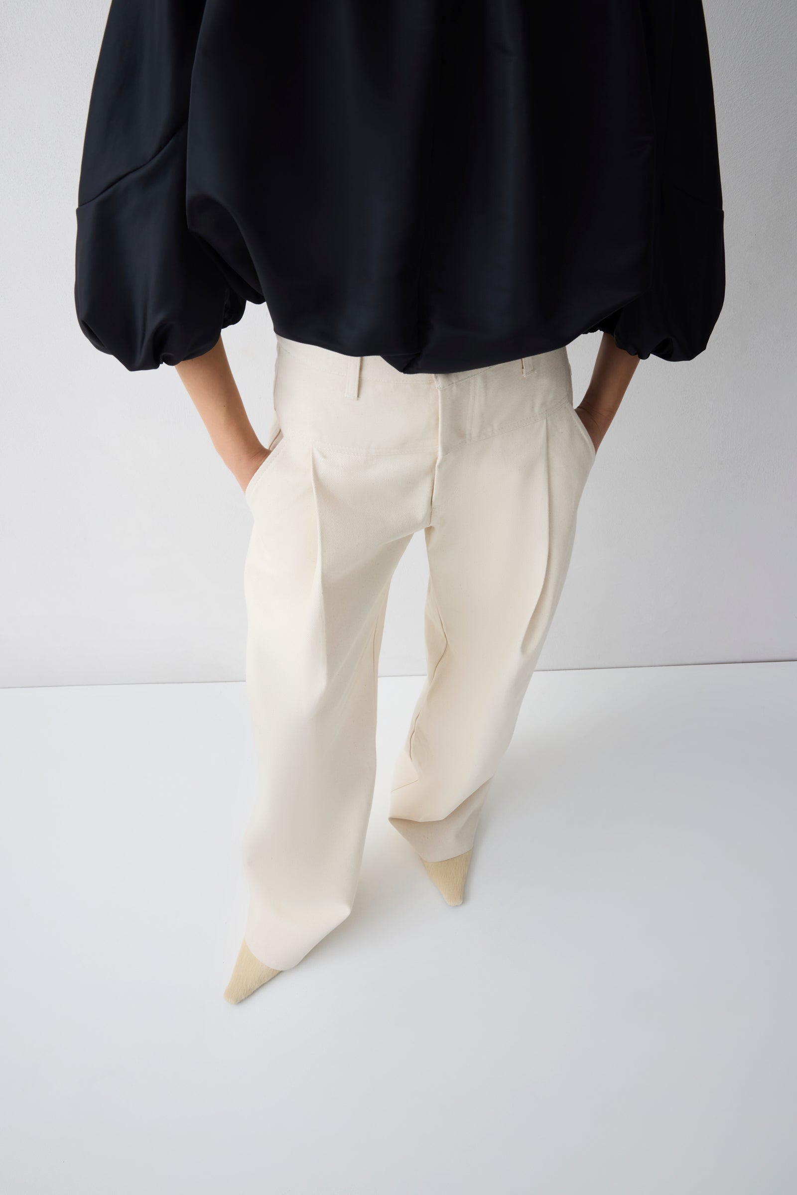Person wearing a black top and white pants on a white background