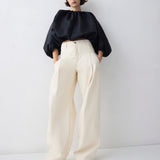 Person wearing a black top and white pants on a white background