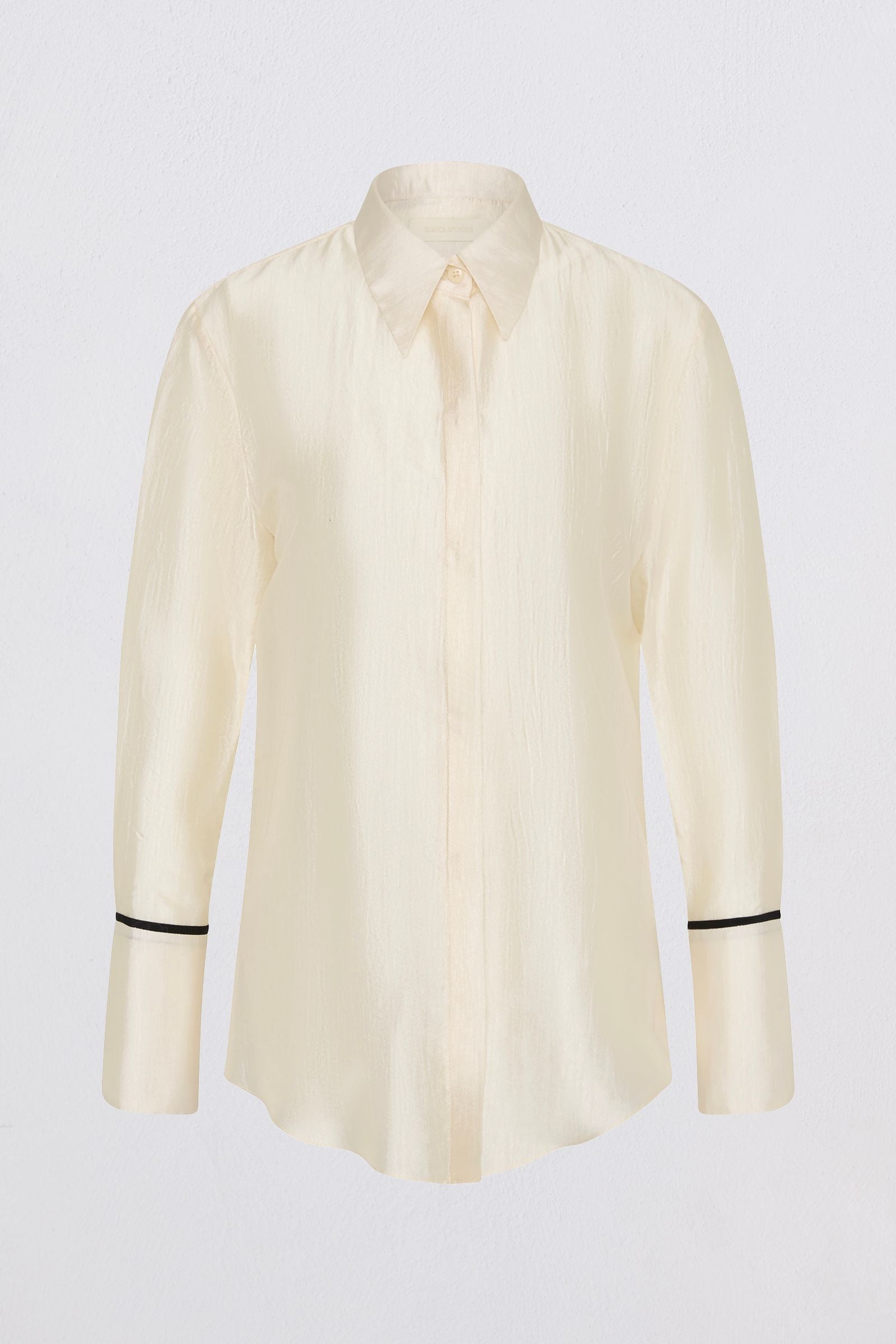 A cream-colored long-sleeve button-up shirt with black piping trim on the cuffs, displayed against a light gray background.