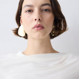 Woman wearing a white top against a plain background