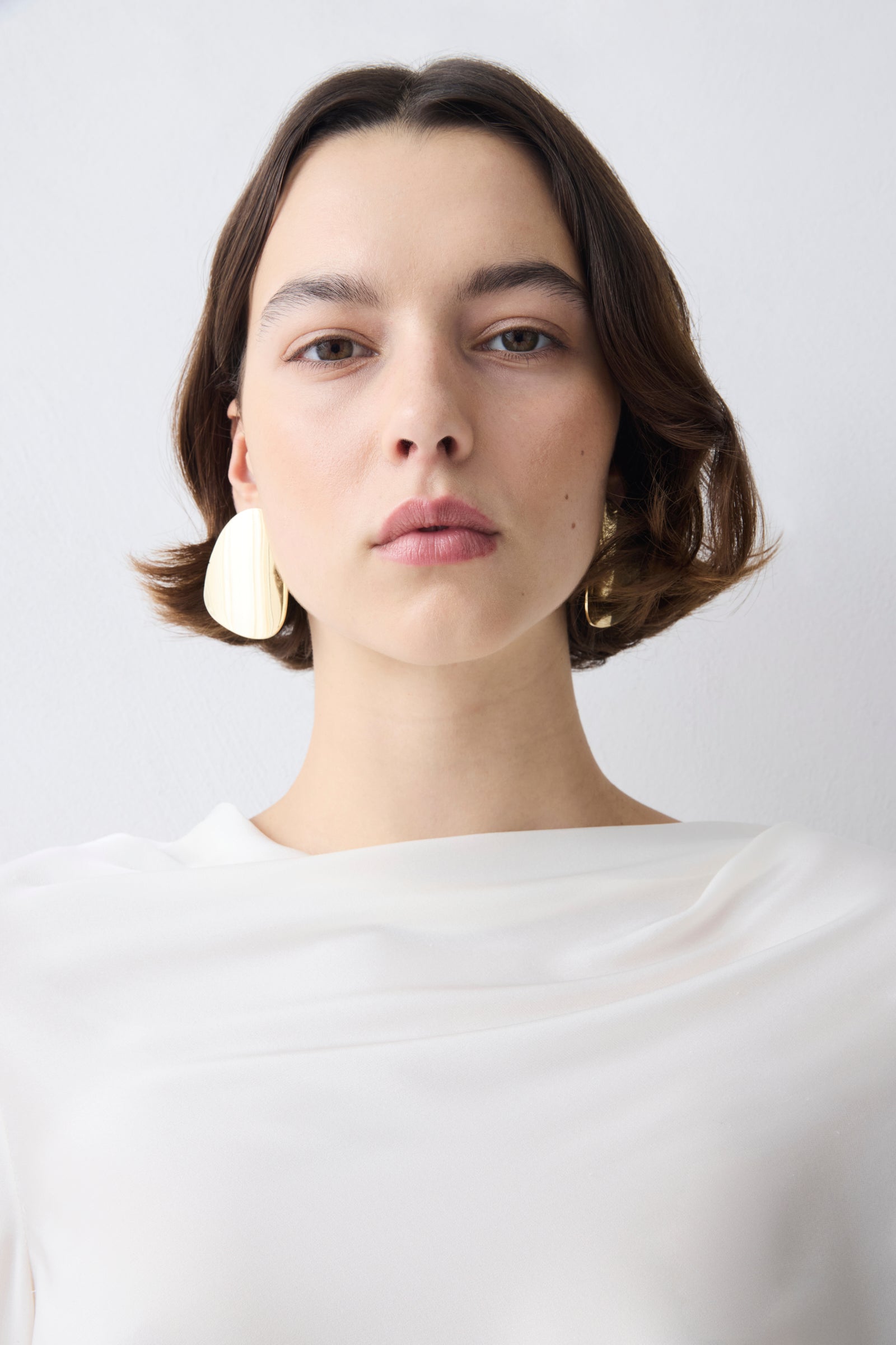 Woman wearing a white top against a plain background