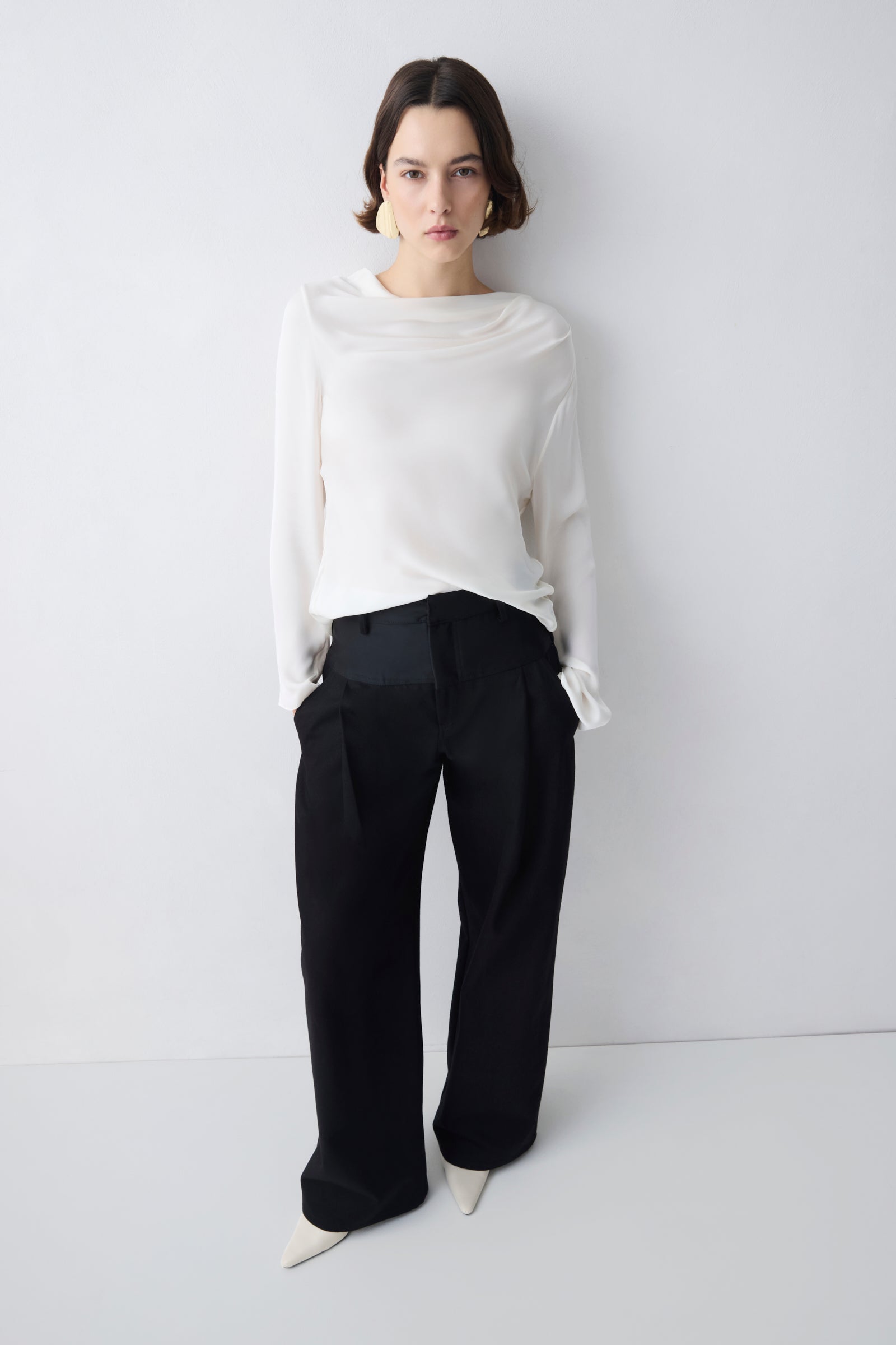 Person wearing a white top and black pants on a plain background