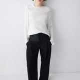 Person wearing a white top and black pants on a plain background
