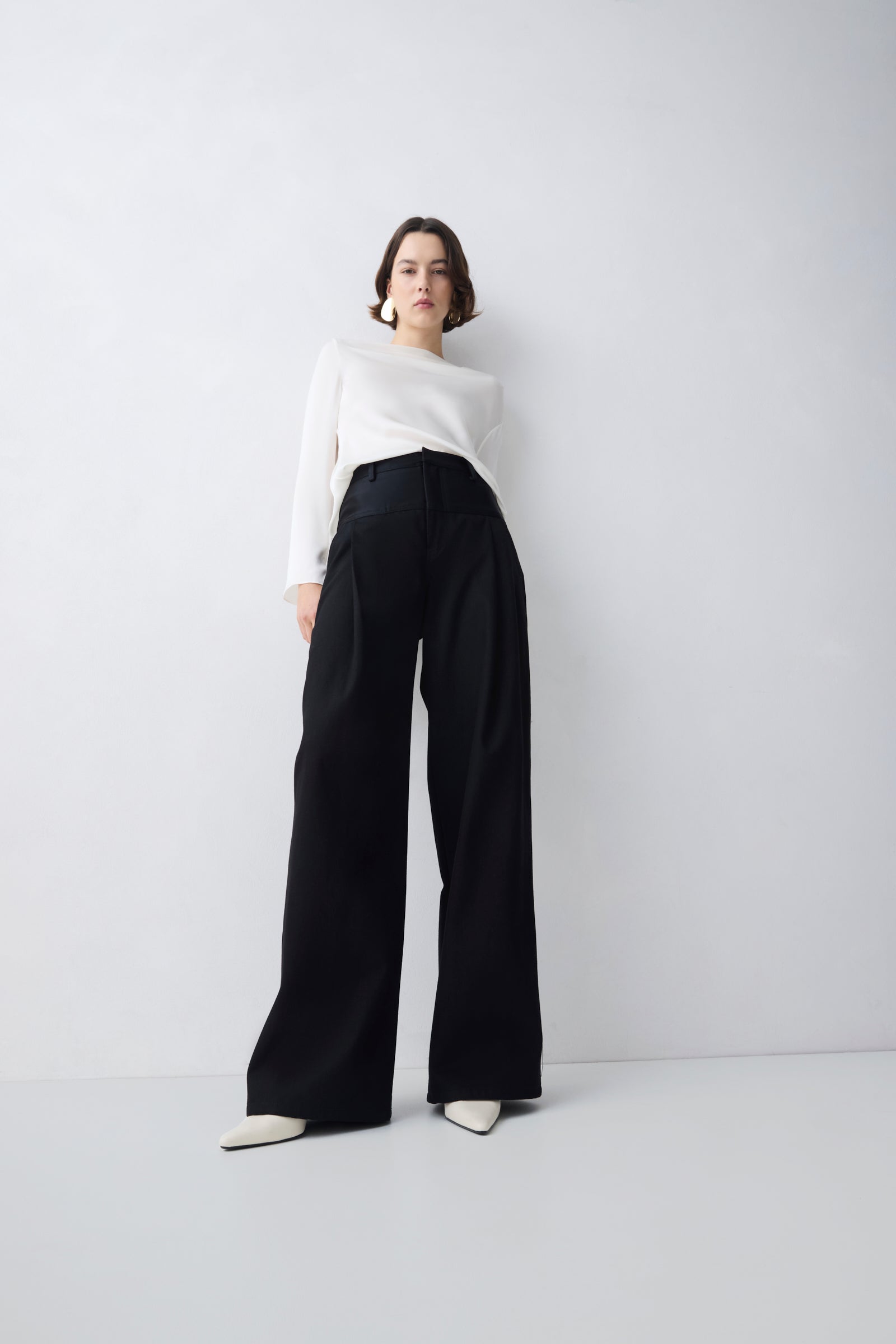 Person wearing a white top and black wide-leg pants on a plain background