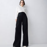 Person wearing a white top and black wide-leg pants on a plain background