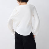 Person wearing a white sweater and black pants against a plain background