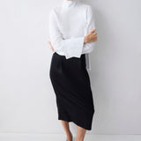 Woman wearing a white blouse and black skirt against a white background