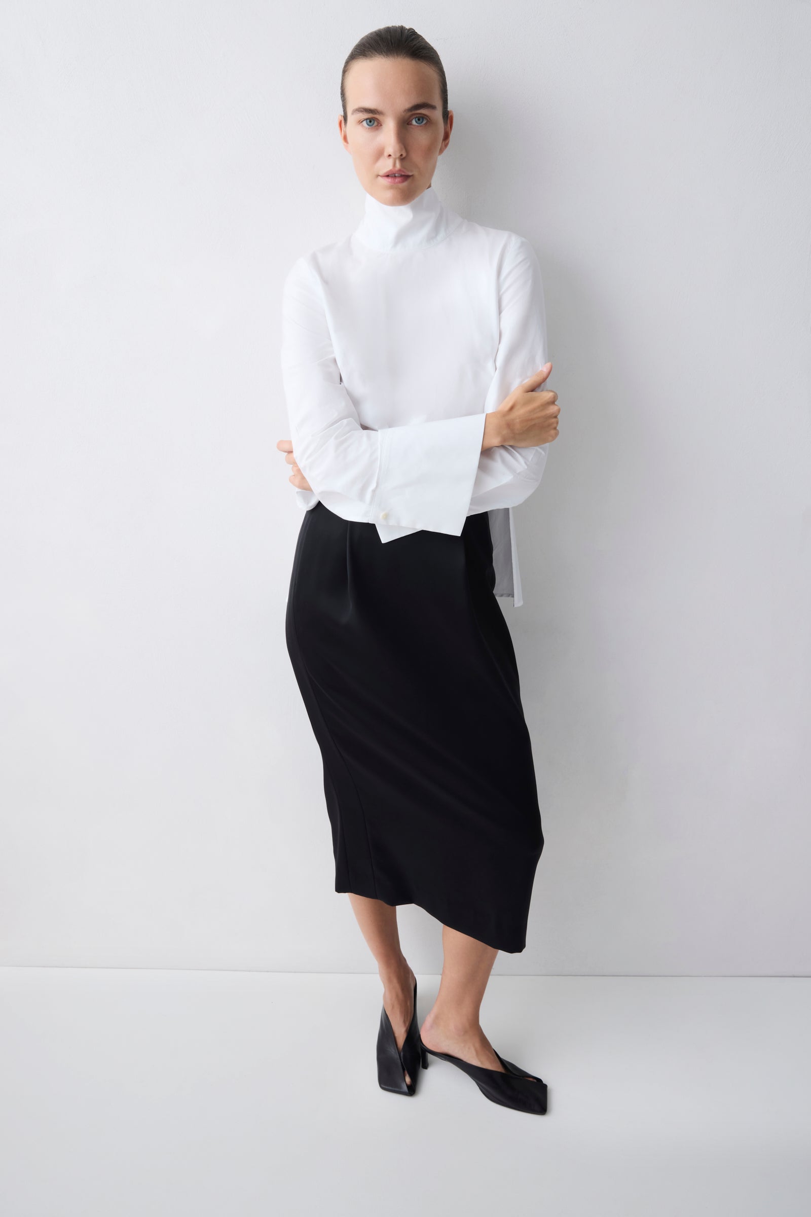 Woman wearing a white blouse and black skirt against a white background