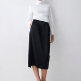 Woman wearing a white turtleneck and black skirt on a white background