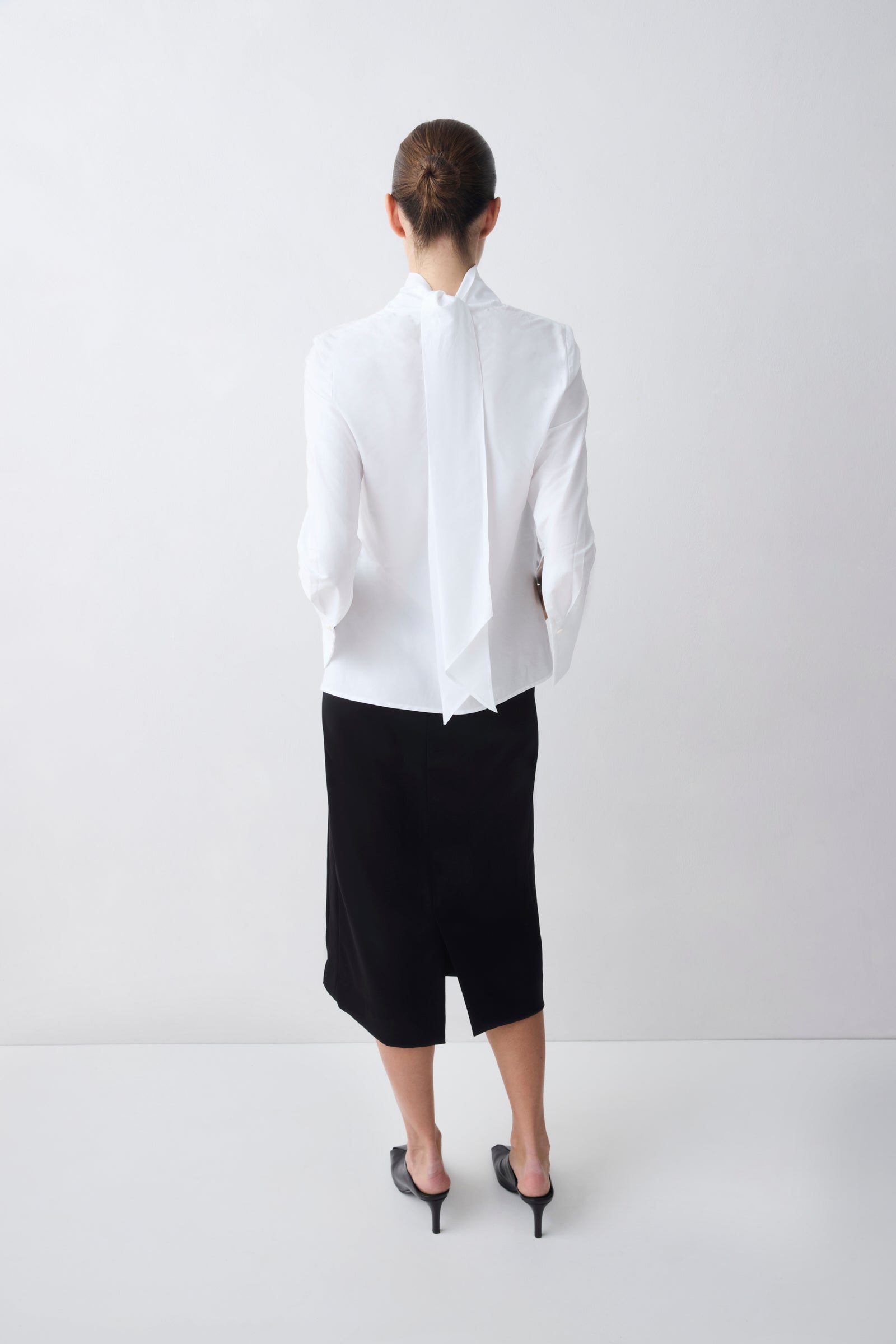 Person wearing a white shirt and black skirt on a white background