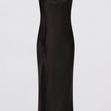 A sleeveless black satin midi dress with a draped cowl neckline and a side slit, shown against a plain light gray background.