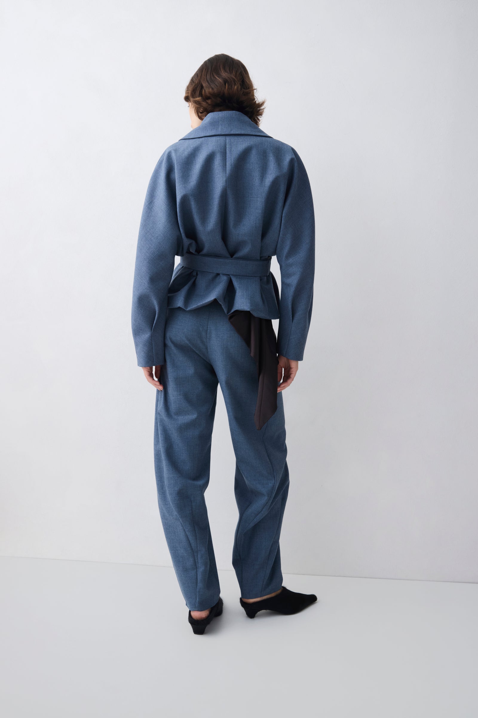 Person wearing a blue jumpsuit standing against a white background