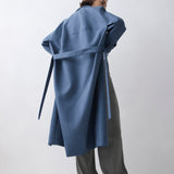 Person wearing a blue coat with a belt on a white background