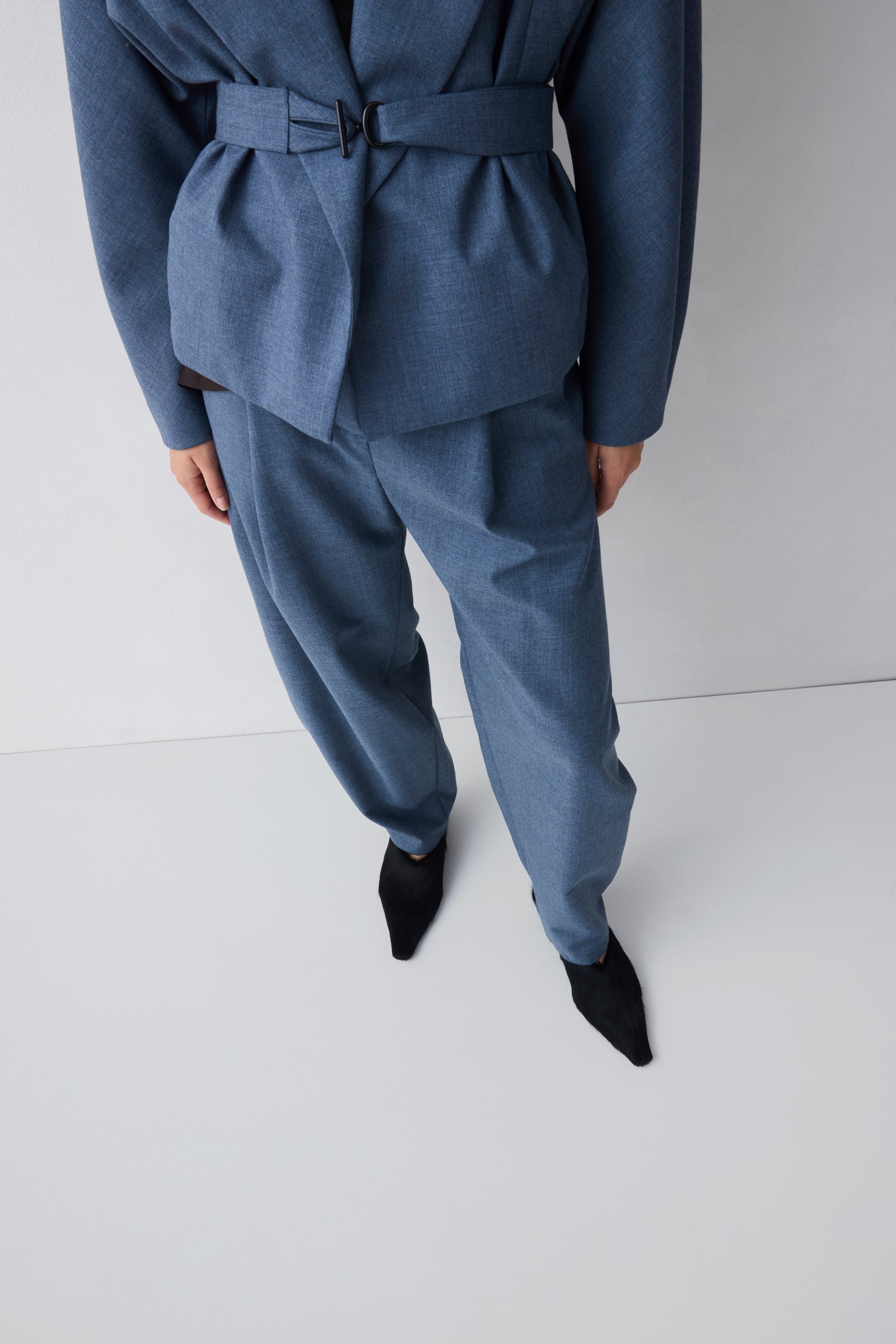 Person wearing a blue suit with a belt on a white background
