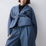 Person wearing a blue coat and pants against a plain background