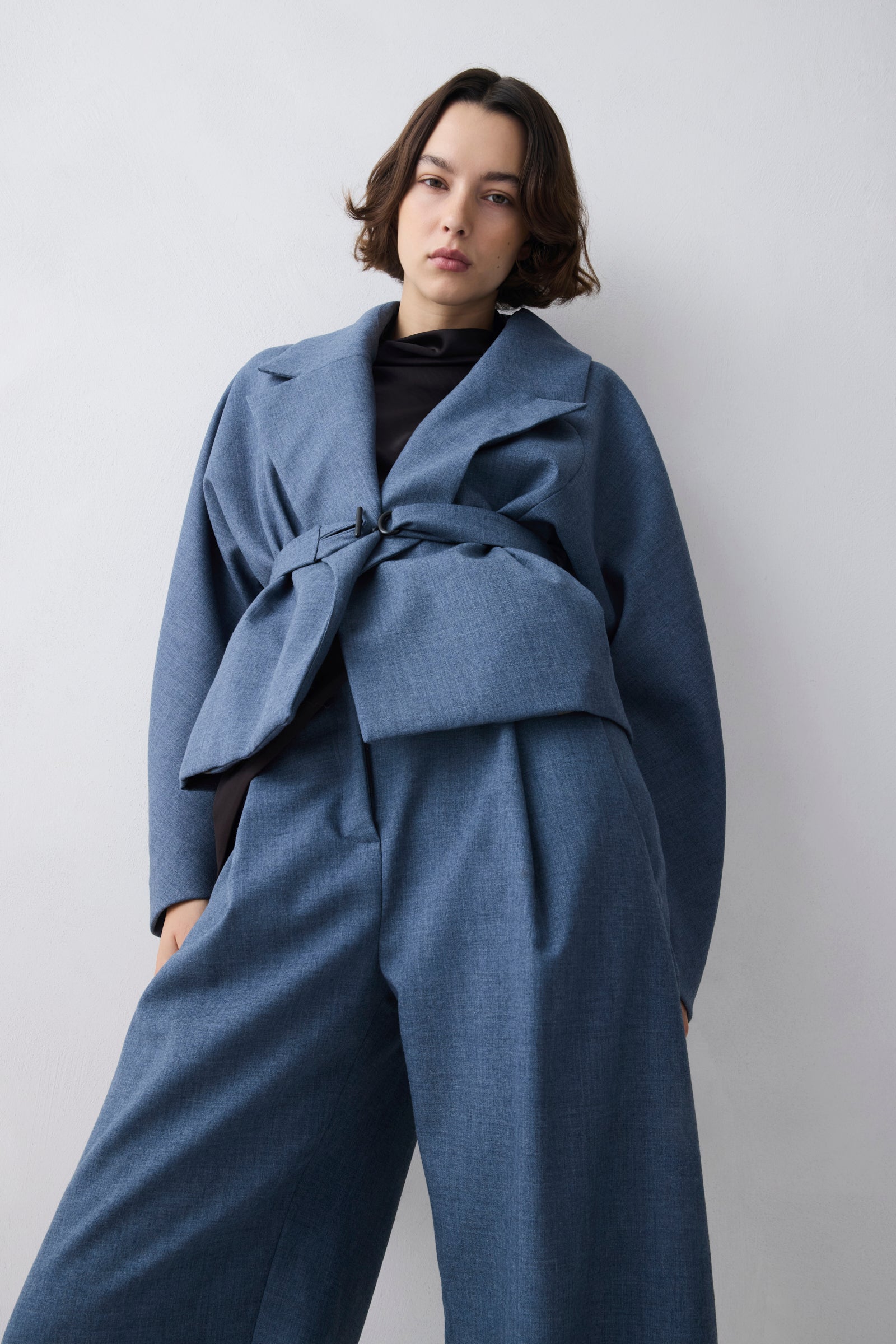 Person wearing a blue coat and pants against a plain background