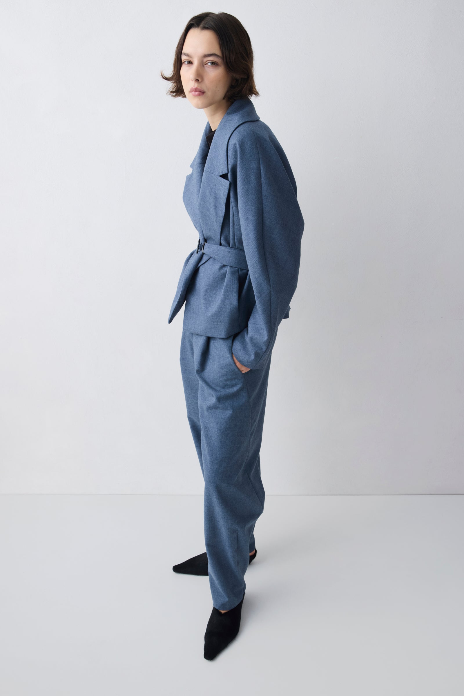 Person wearing a blue outfit with a belt on a white background