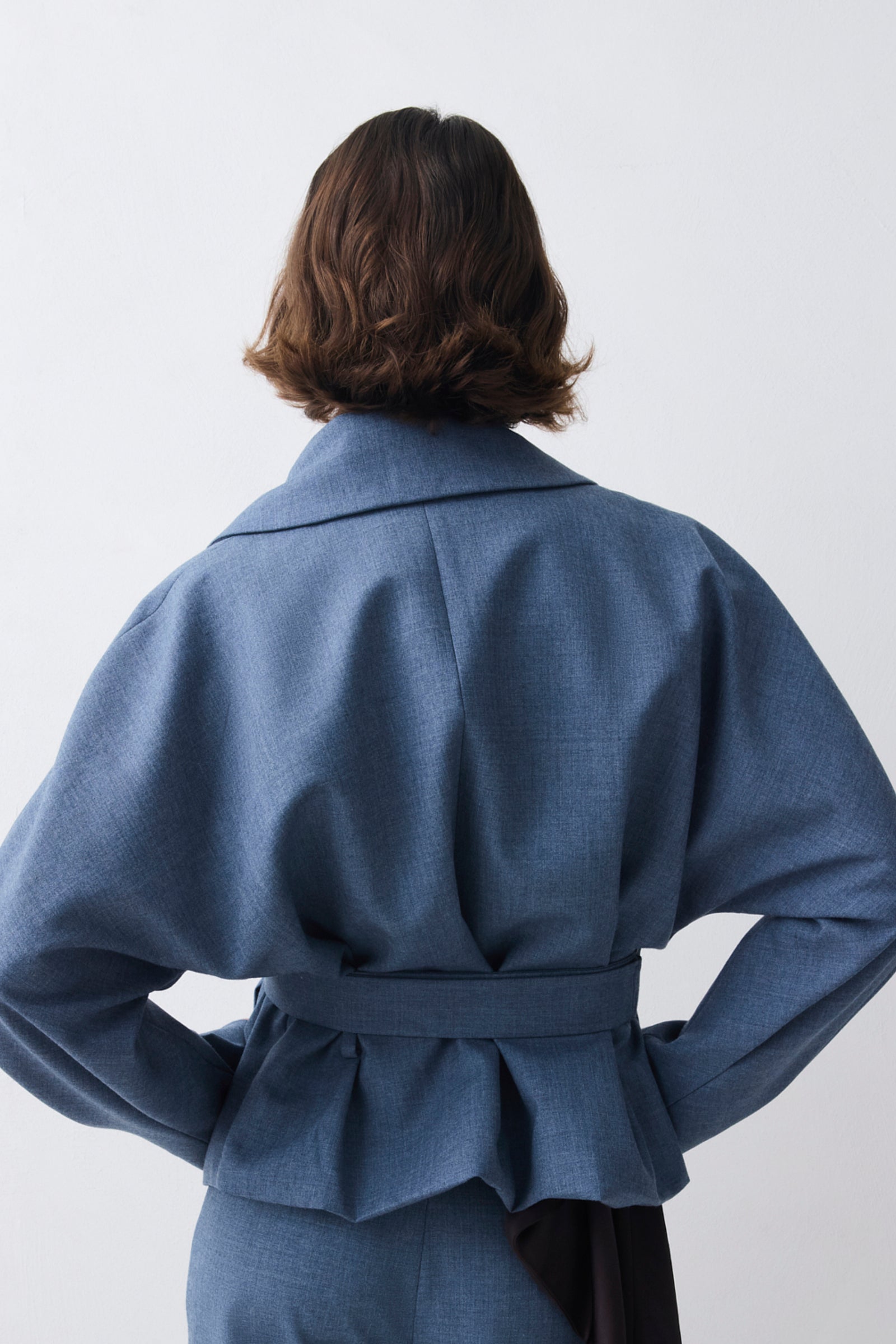 Person wearing a blue coat with a plain background